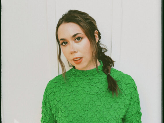 A portrait of a woman wearing a green sweater with her hair in a braid
