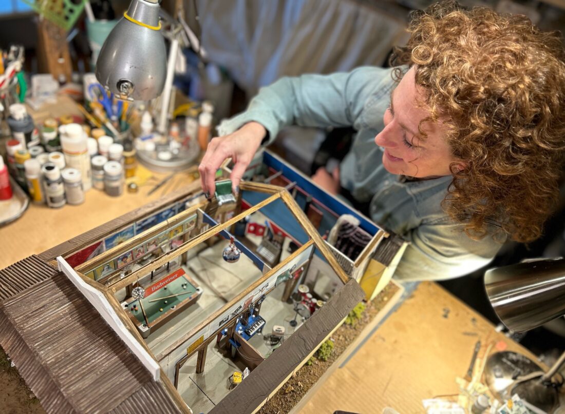 A woman reaches into a miniature model of a juke joint.
