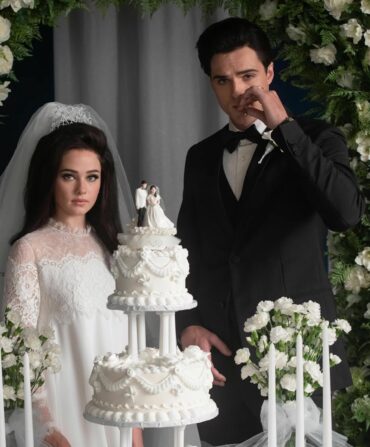 Actors as Priscilla and Elvis Presley by a wedding cake