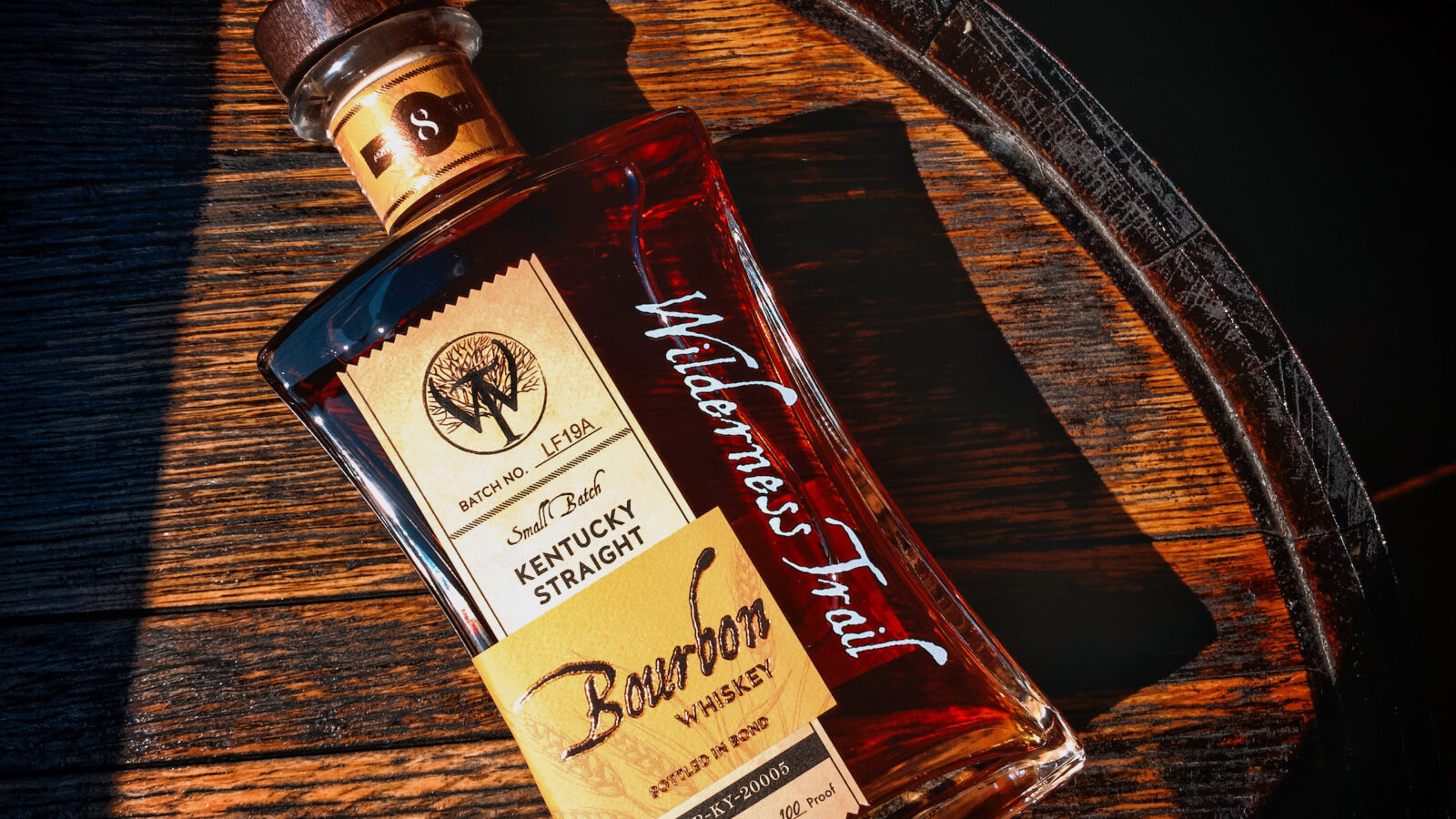 A bottle of bourbon on a wood barrel