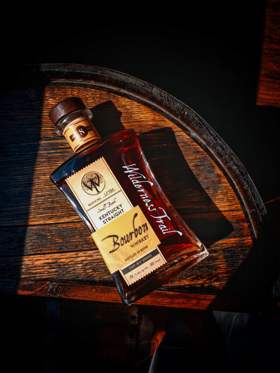 A bottle of bourbon on a wood barrel