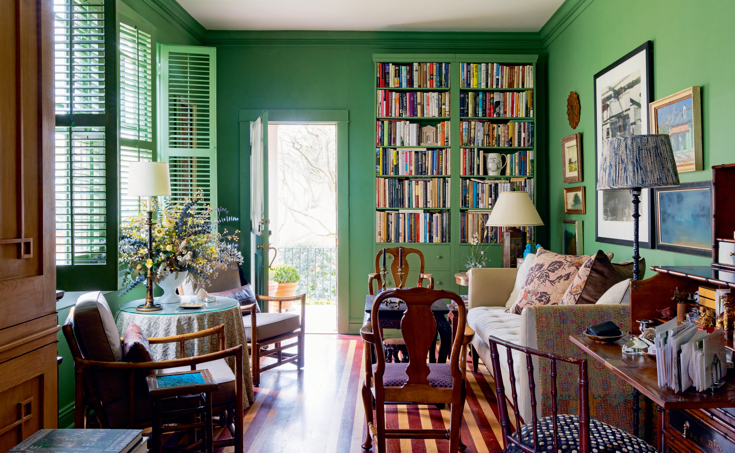 An emerald green room with a striped wood floor and open windows.