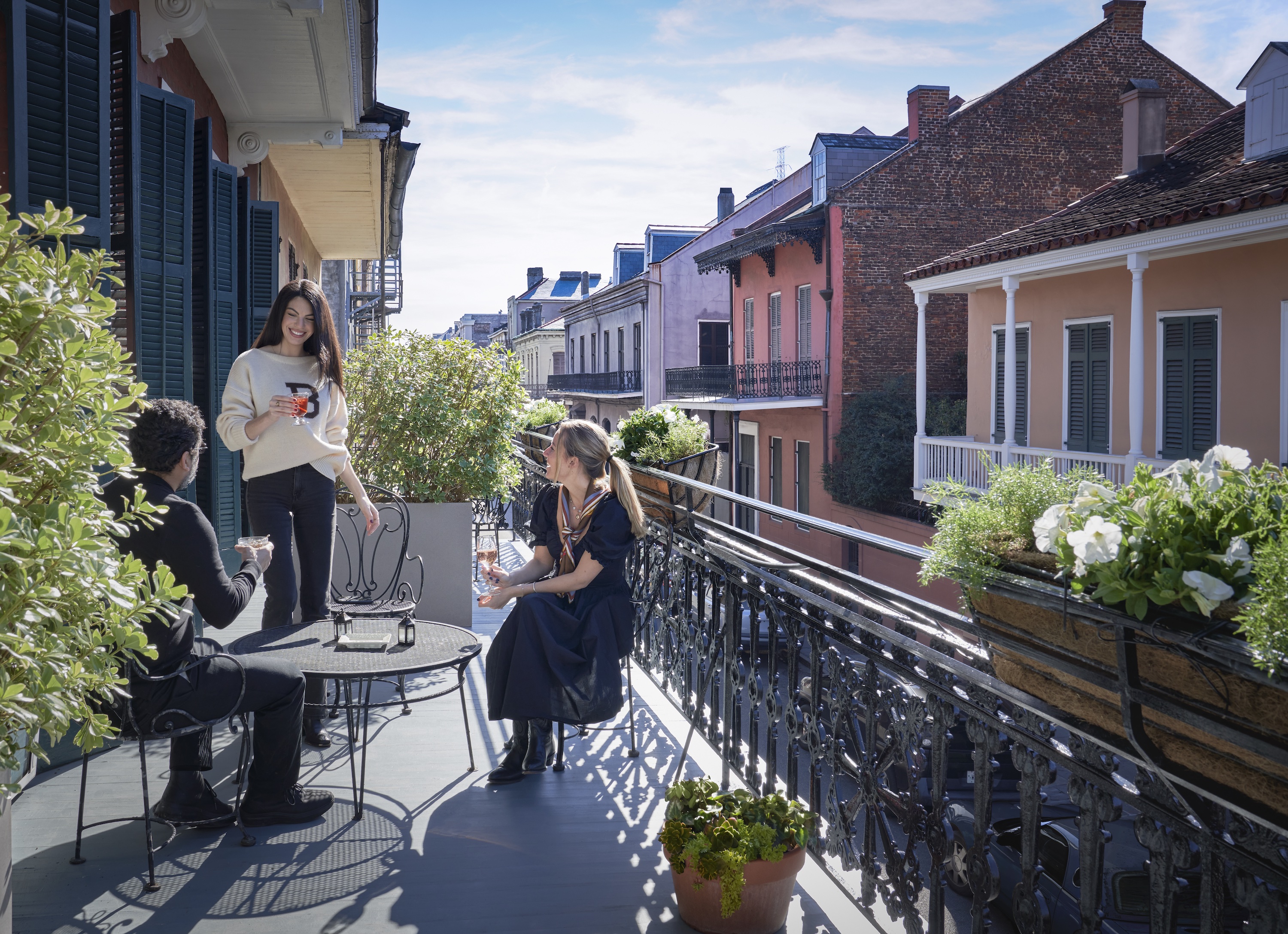 A balcony with three people enjoying a drink