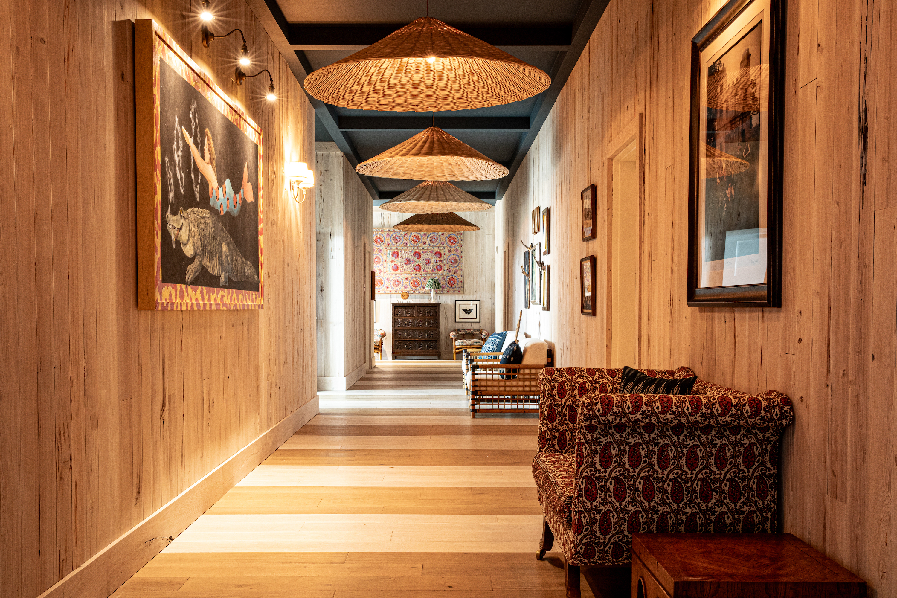A wood paneled corridor with large rattan light fixtures.