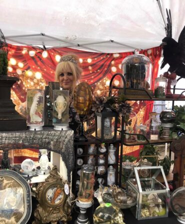 A women in a tent with halloween items for sale.