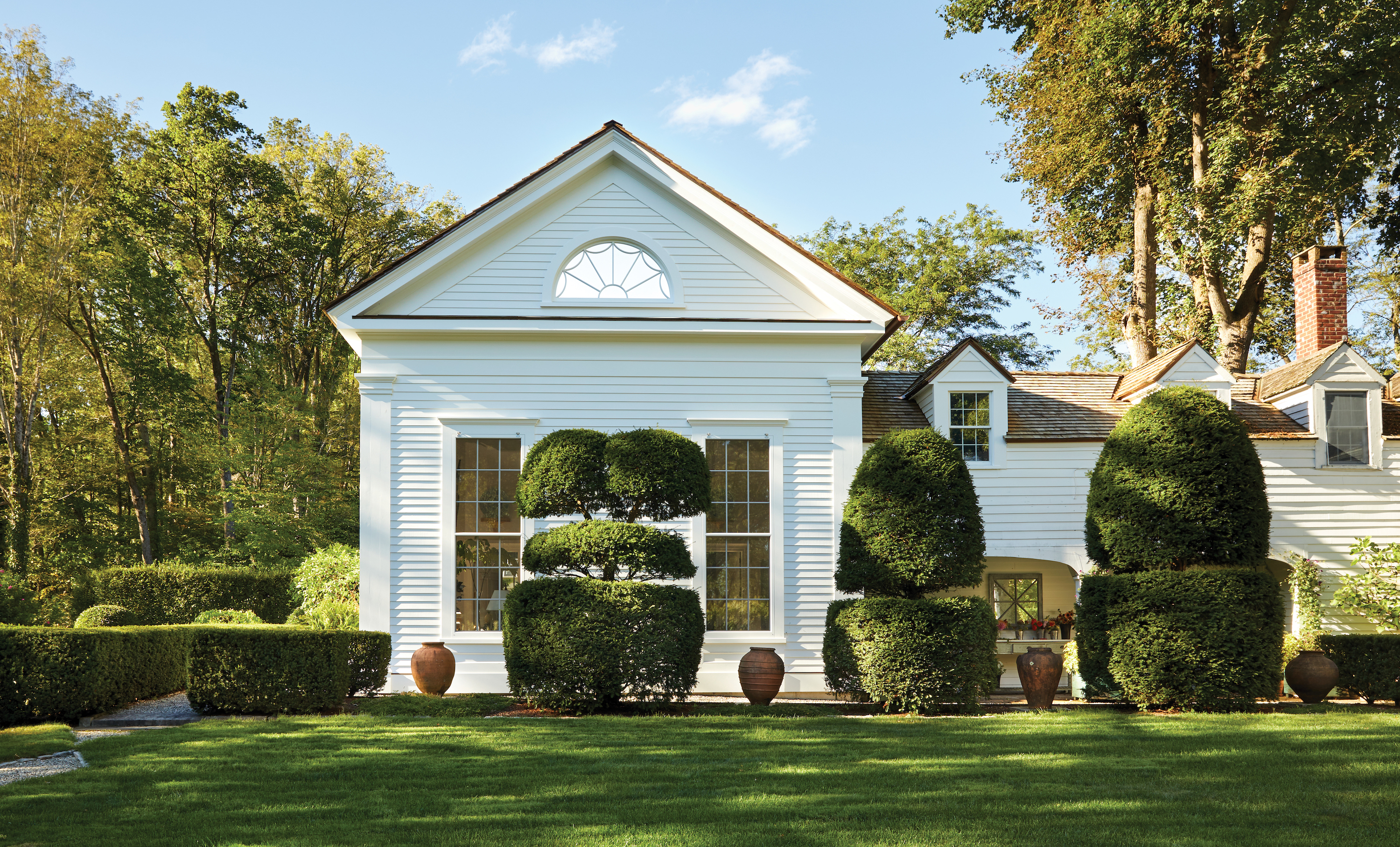 A white house with trimmed boxwoods outside