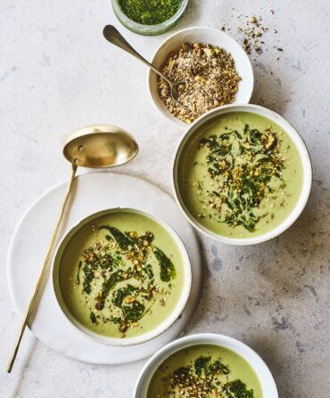 Bowls of green ramp and potato soup on a marble background