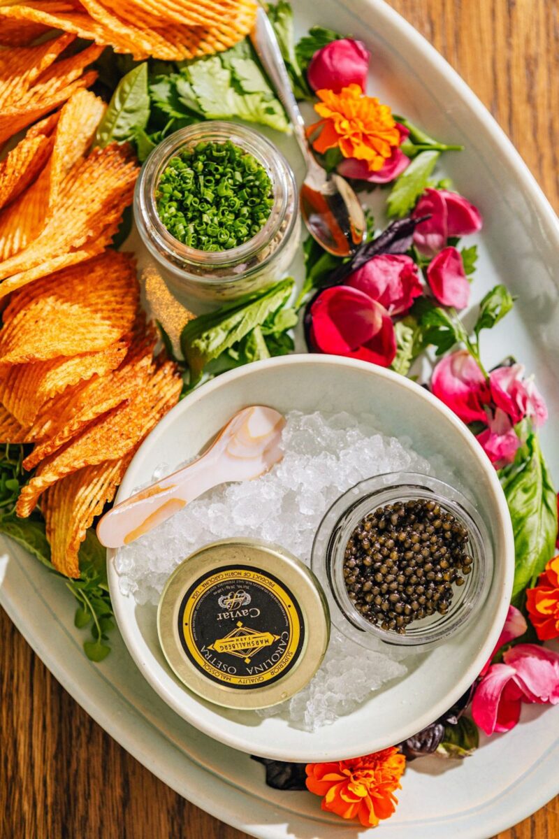 A plate with sliced veggies, chips, and caviar