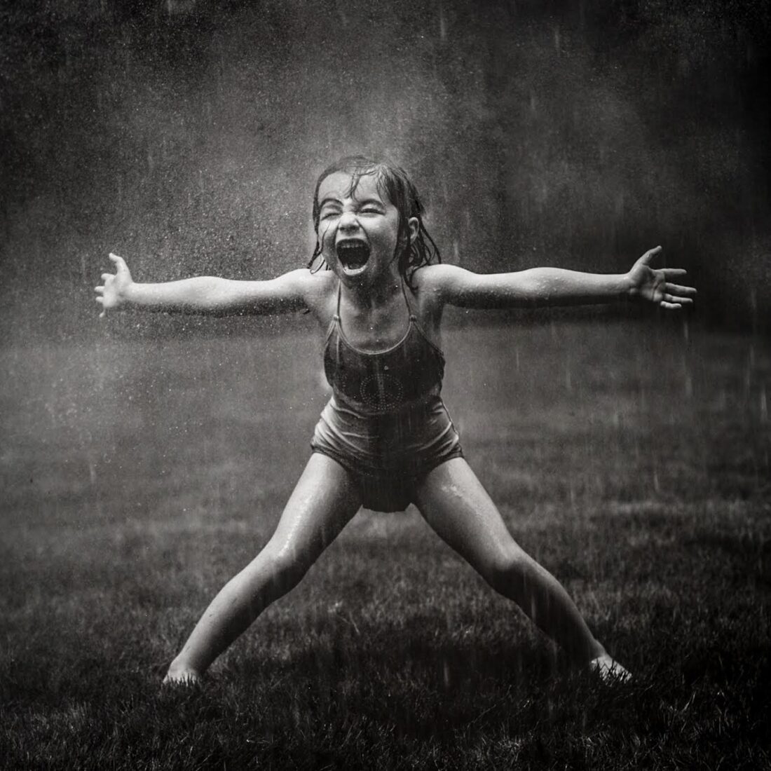 A black and white photo of a little girl in the rain