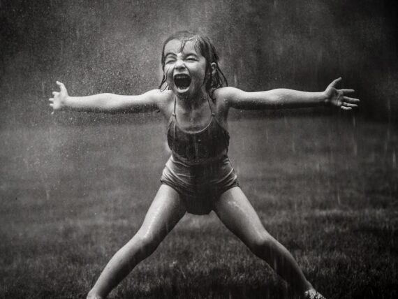 A black and white photo of a little girl in the rain