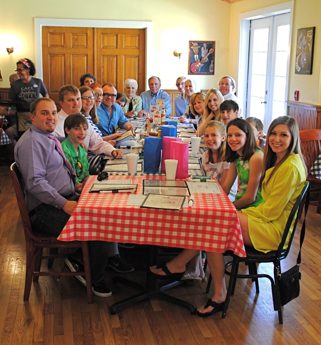 A family sits in a restaurant at a checked red and white table.