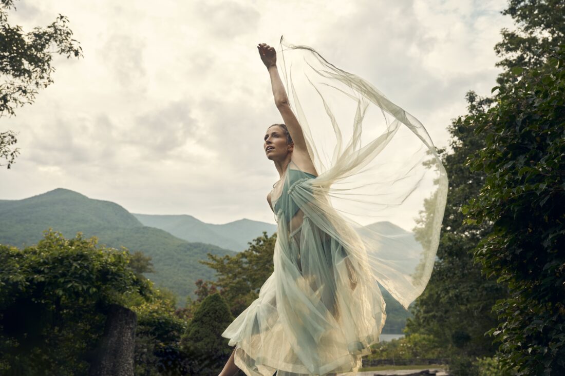 A dancer in gauzy fabric twirls against the backdrop of the blue ridge mountains