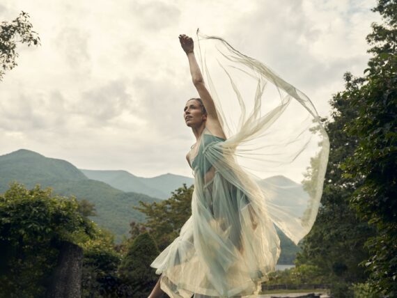 A dancer in gauzy fabric twirls against the backdrop of the blue ridge mountains