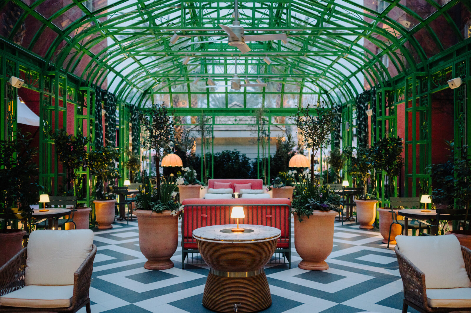 An art-deco green wrought-iron courtyard with vines, plants, and seating.