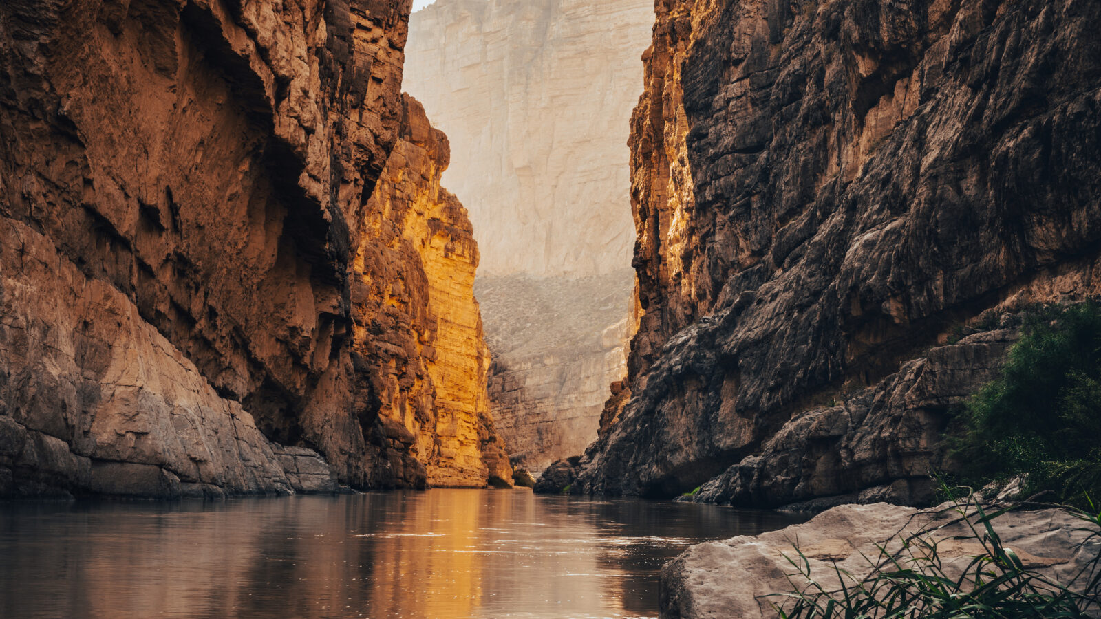 A river snakes through a sunlit canyon
