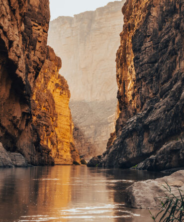 A river snakes through a sunlit canyon