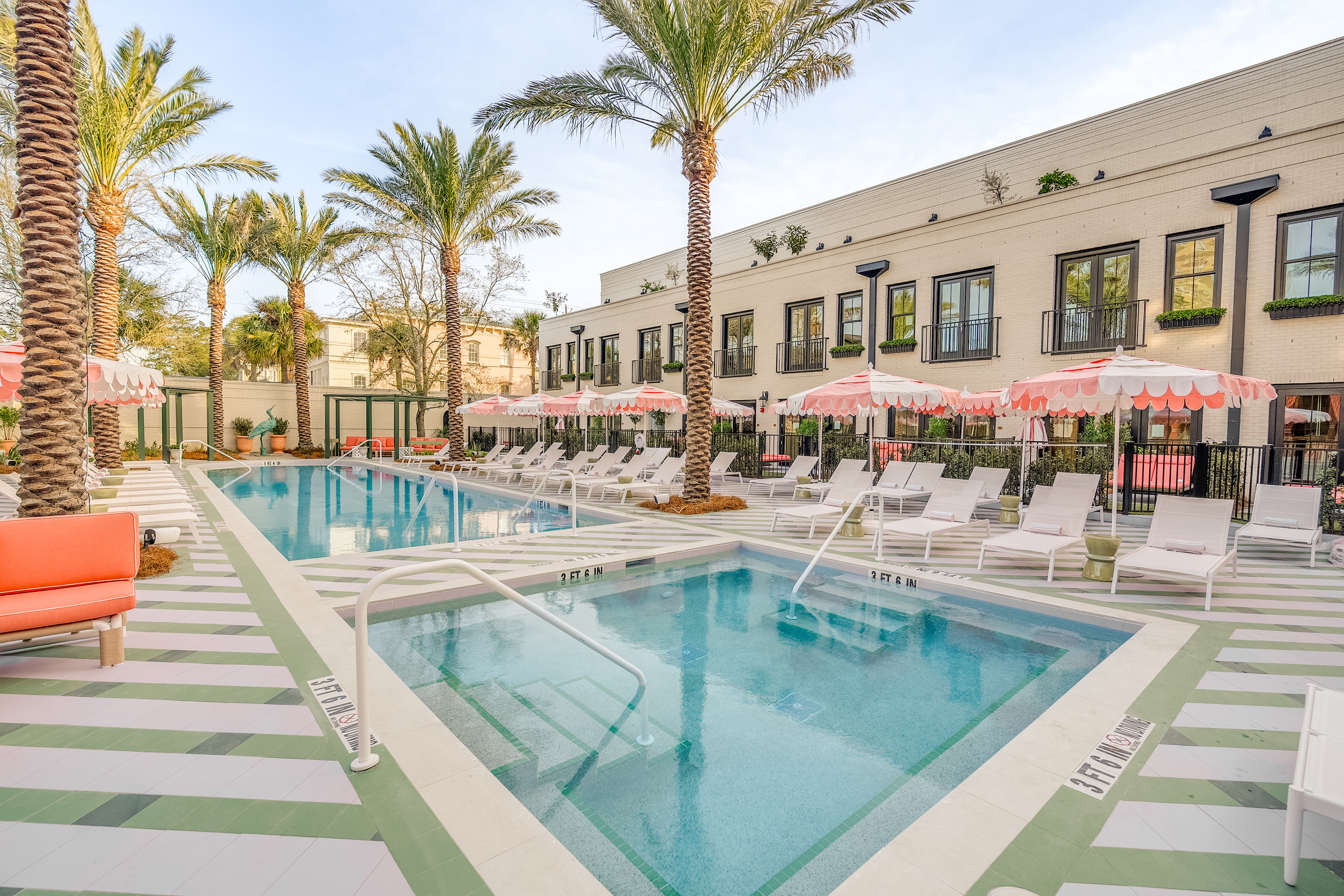 A hotel pool piazza with pink umbrellas, lounge chairs, and striped floor detailing