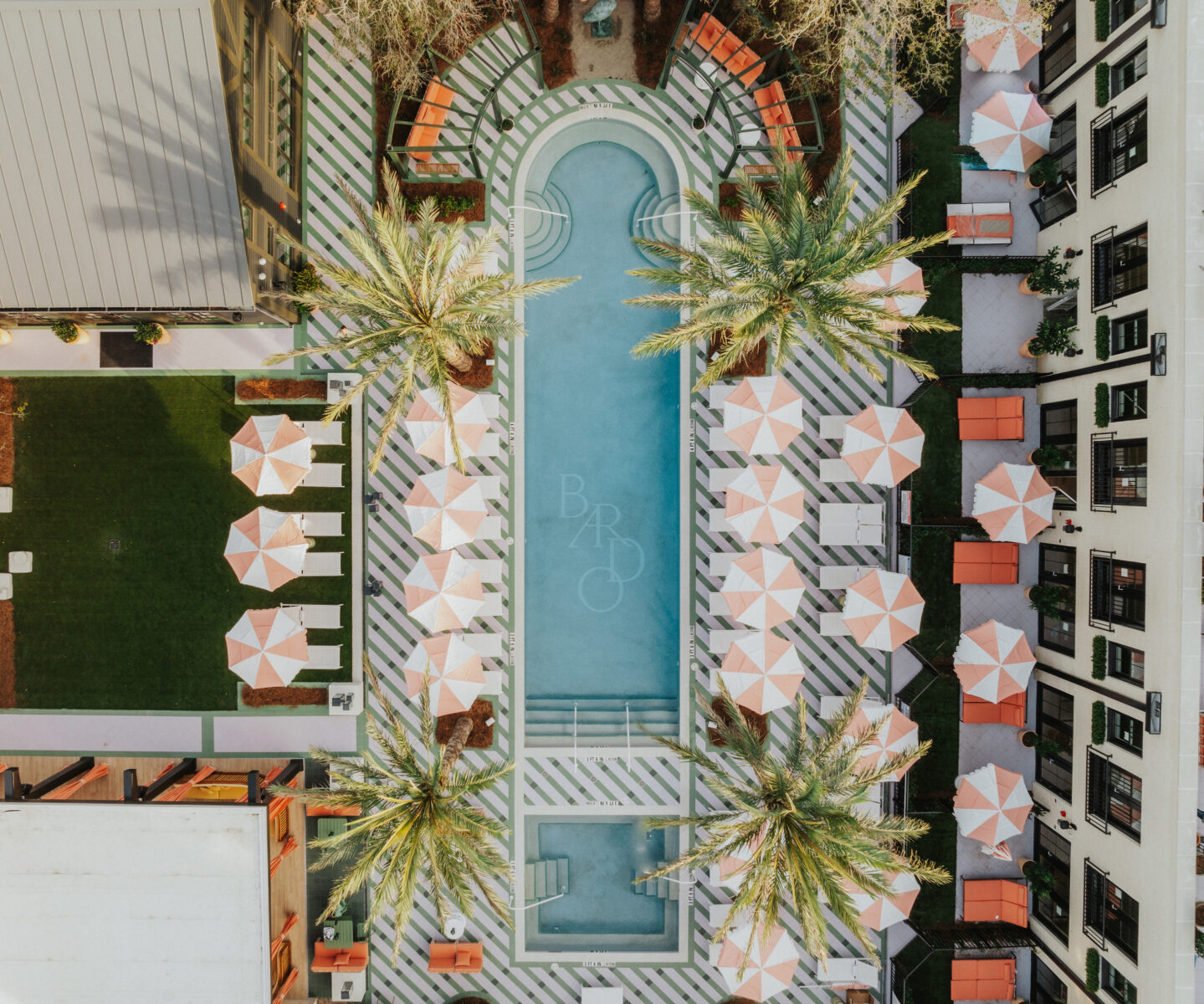 An aerial of the pool and its striped umbrellas.