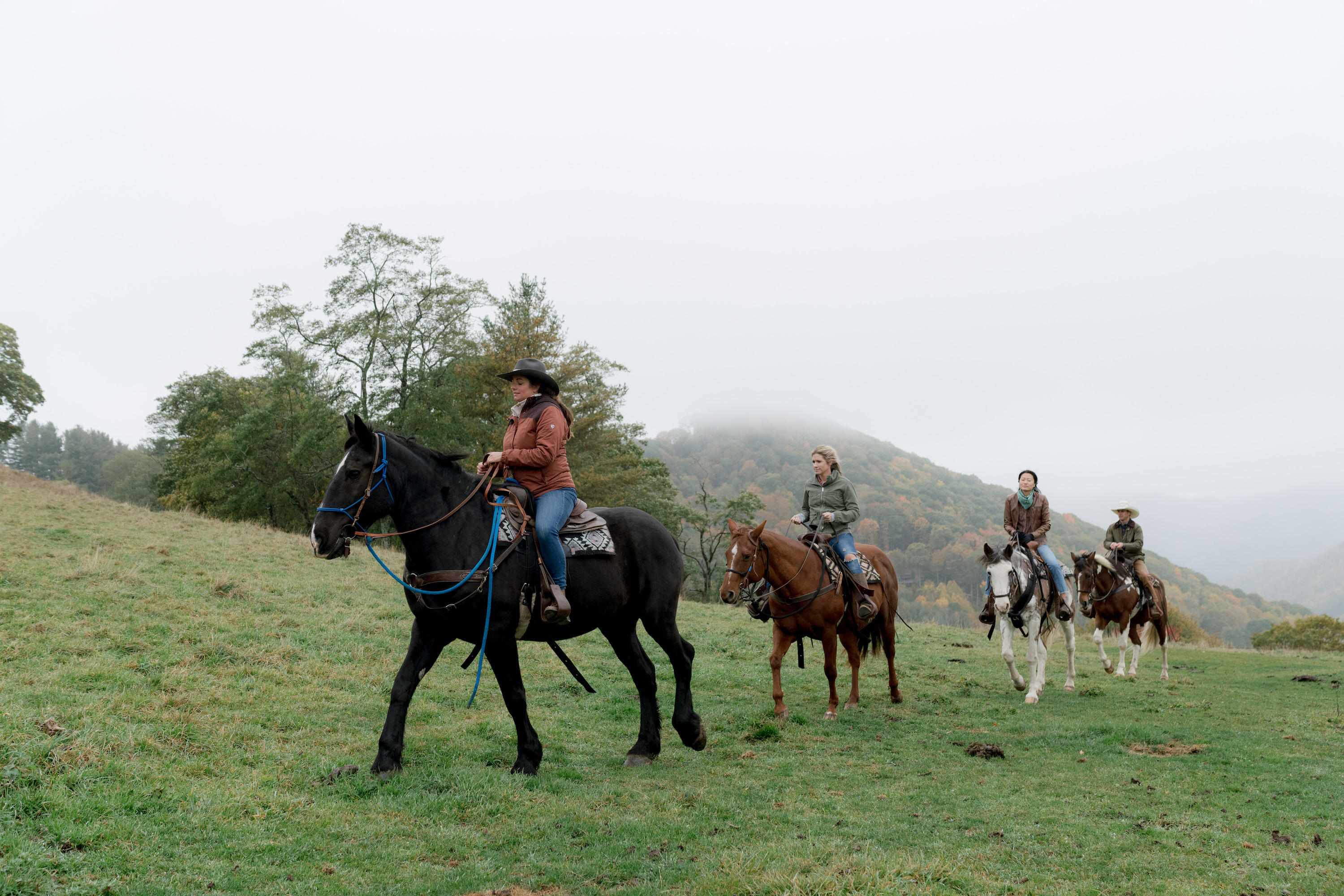 A group of riders and horses go through a mountain landscape