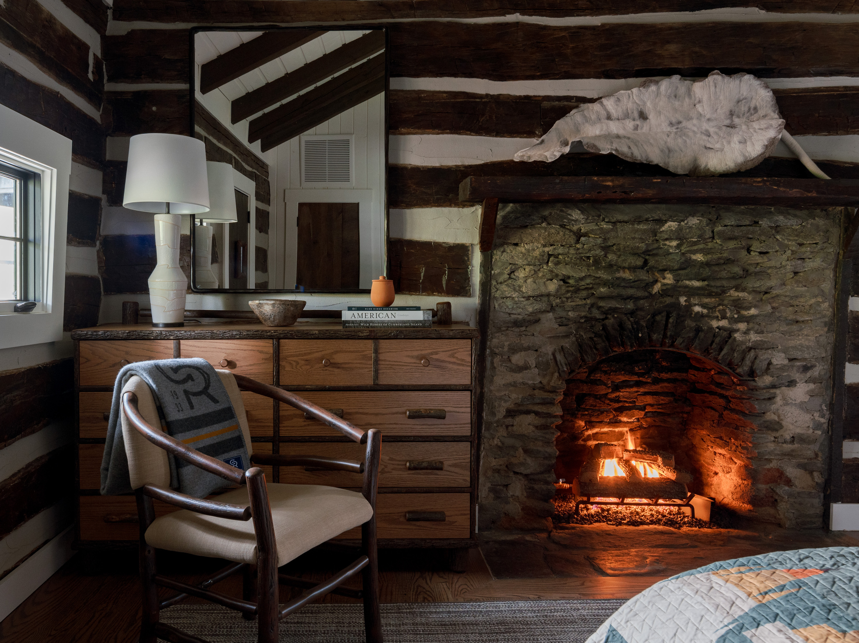 A wall of a guest room with a brick fireplace and chair.