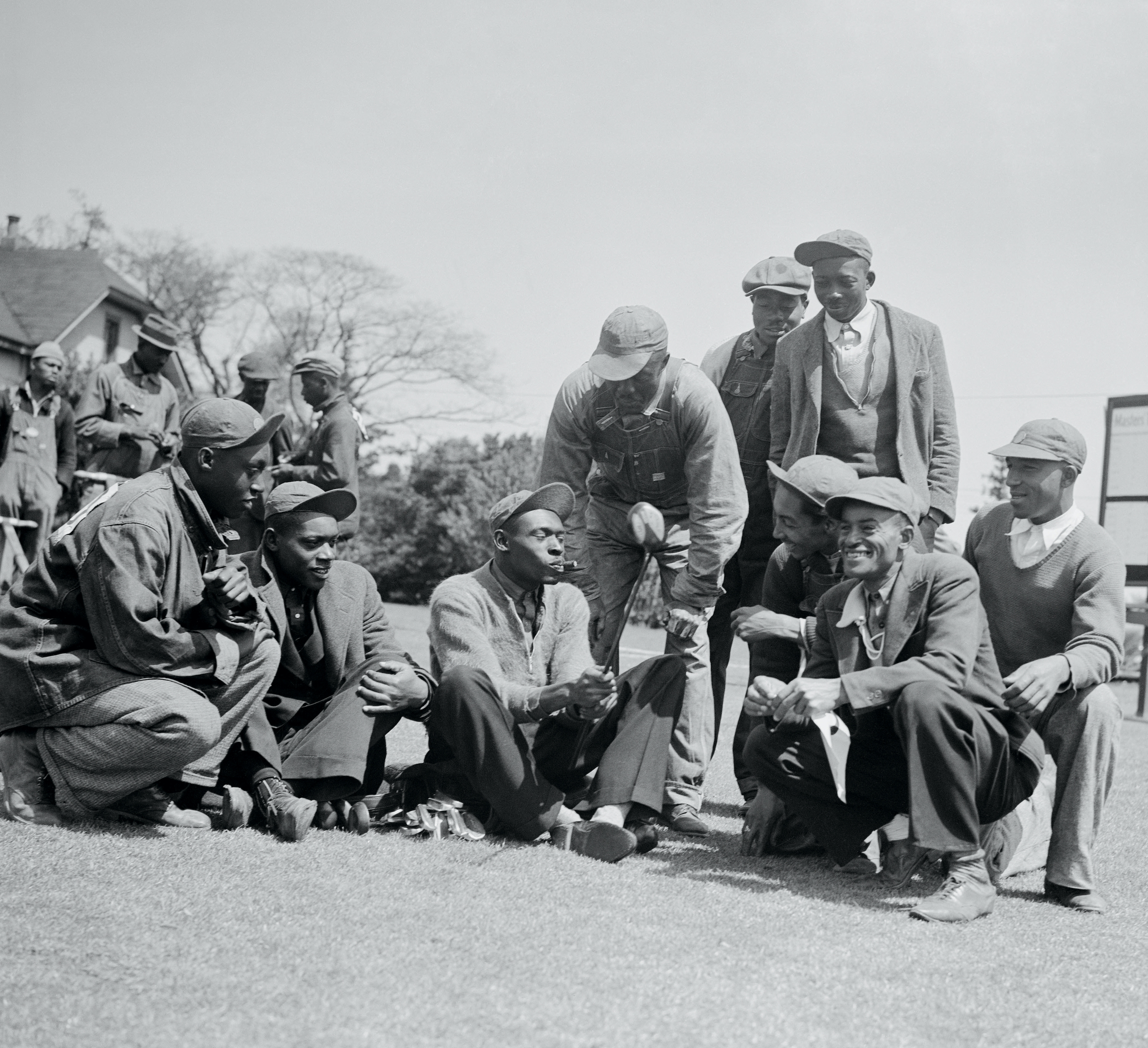 A group of caddies smile and sit on the green