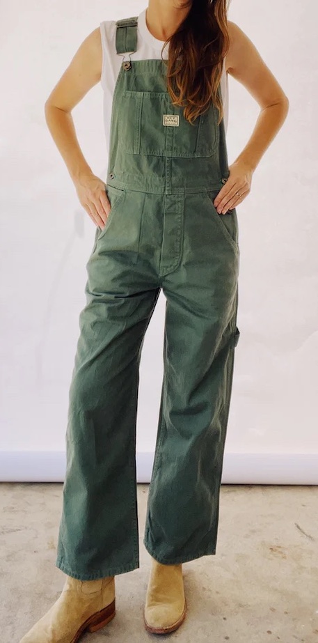 A woman wears dark green overalls