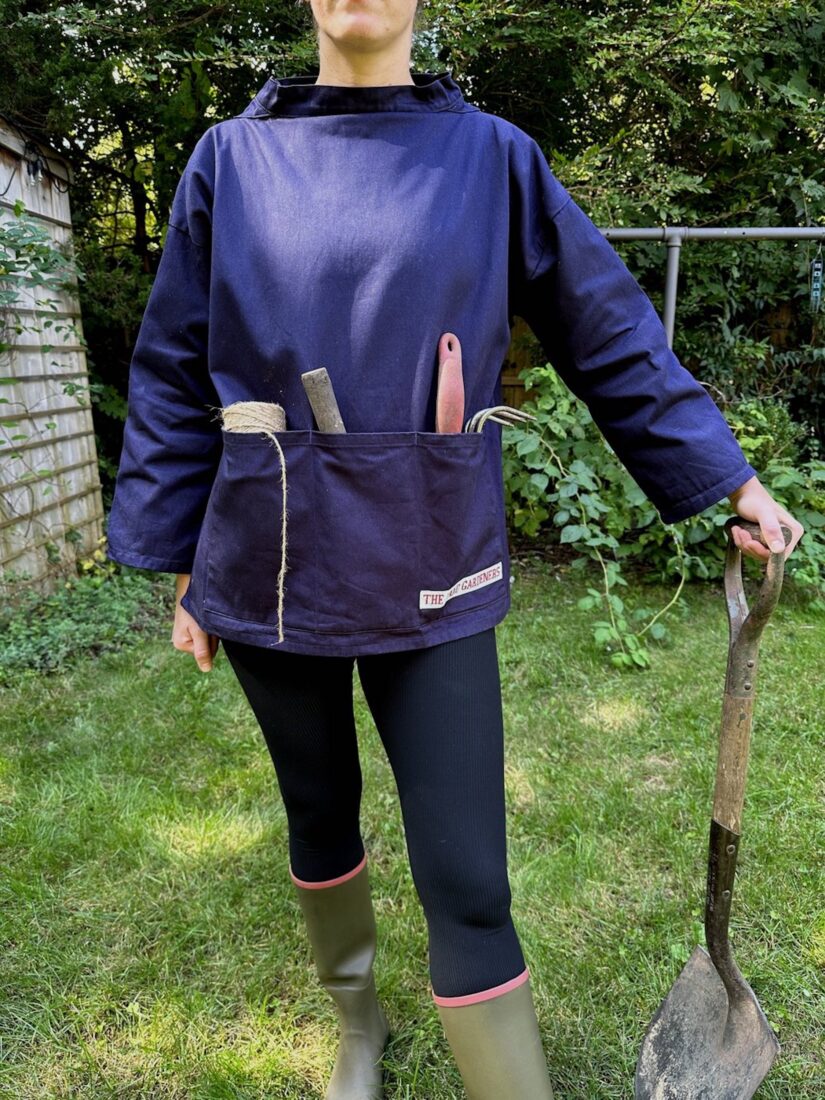 A woman wears a navy smock in the garden