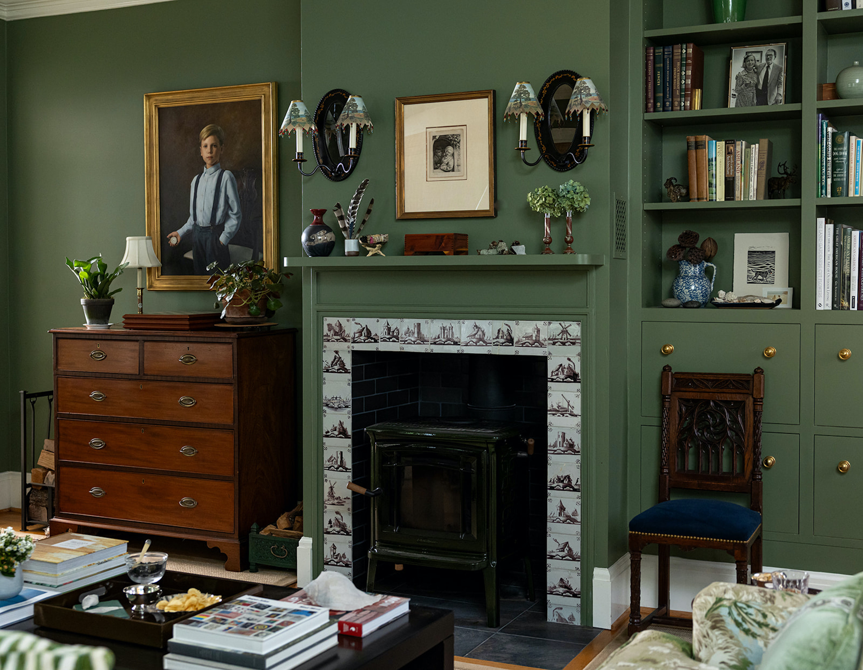 A living room with dark green walls and a tiled fireplace