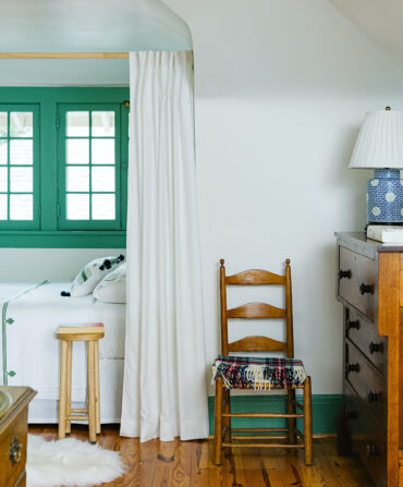 A bedroom with a curtained nook and a bright green window.