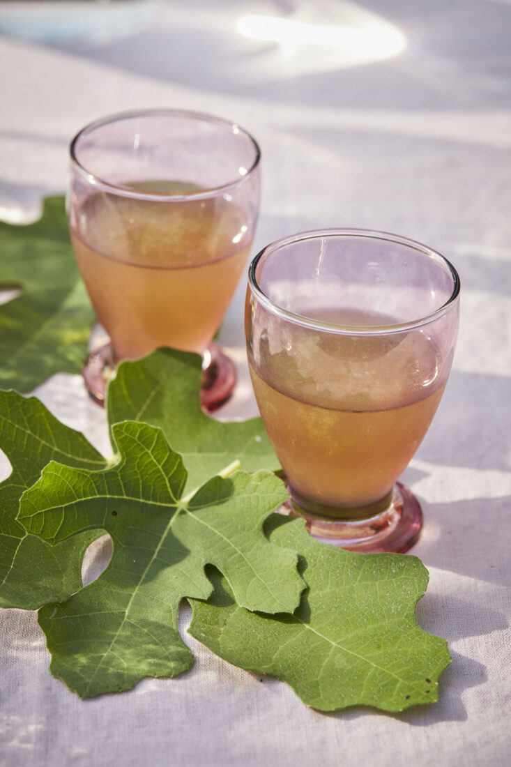 An amber cocktail on top of fig leaves