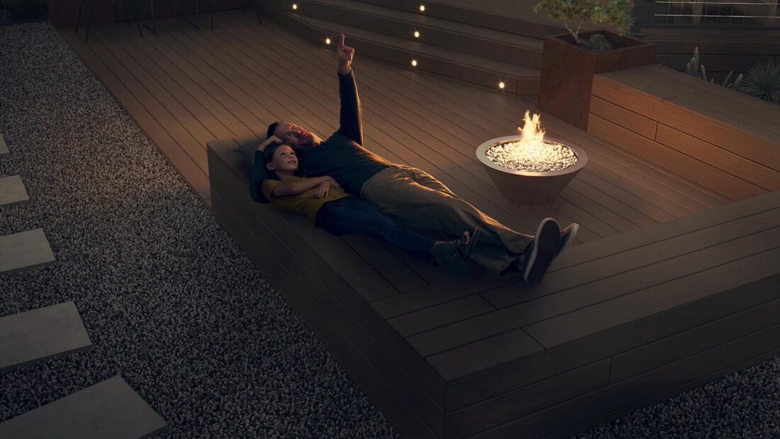 A man and little girl lay on a deck and stargaze