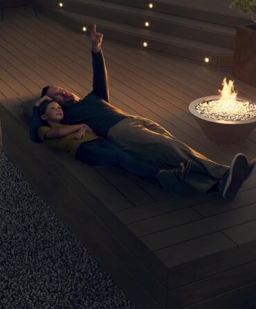 A man and little girl lay on a deck and stargaze
