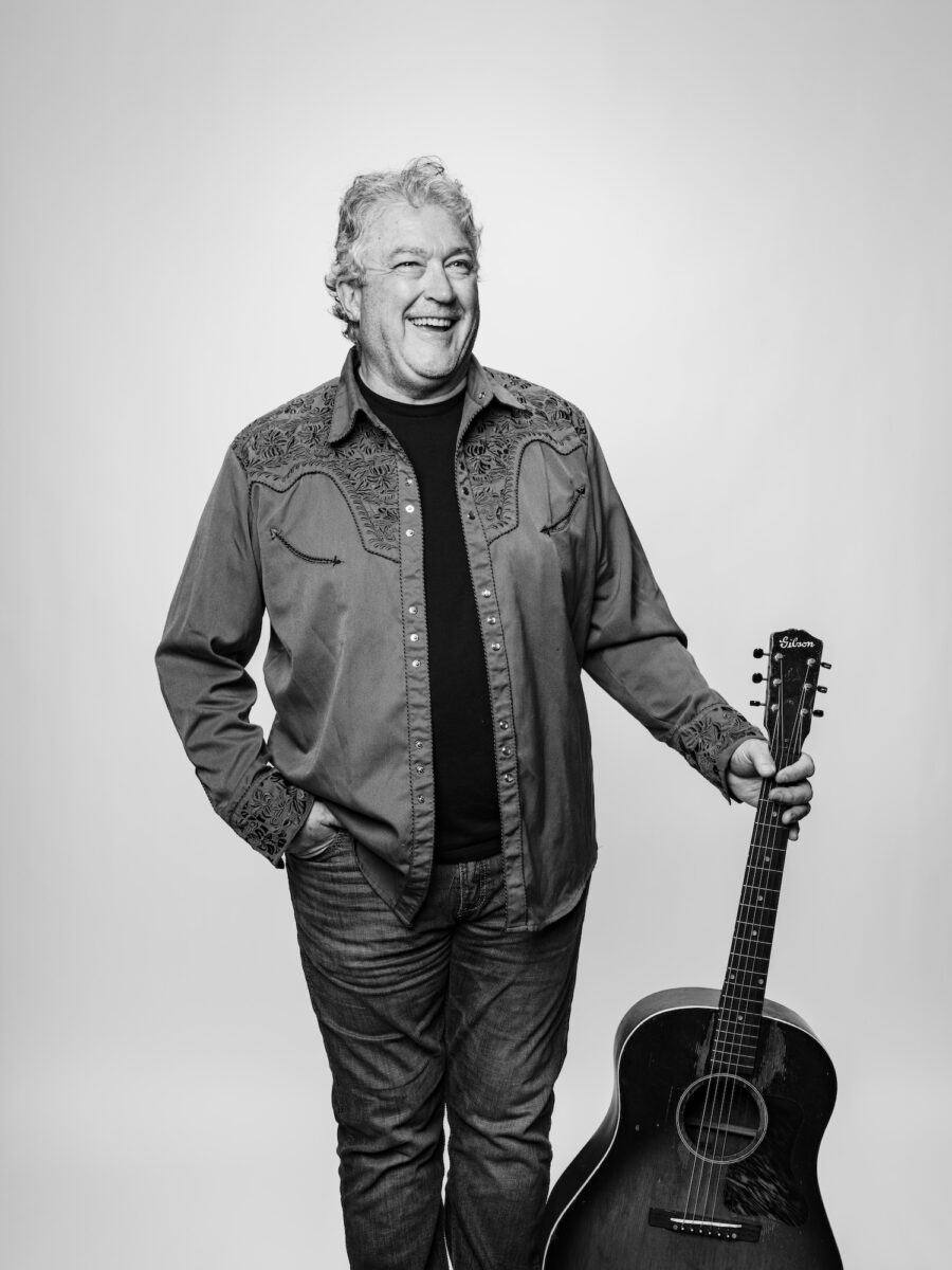 A black and white portrait of a man holding a guitar