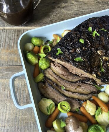 A blue cooking pan with veggies and brisket