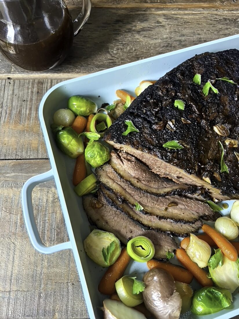 A blue cooking pan with veggies and brisket
