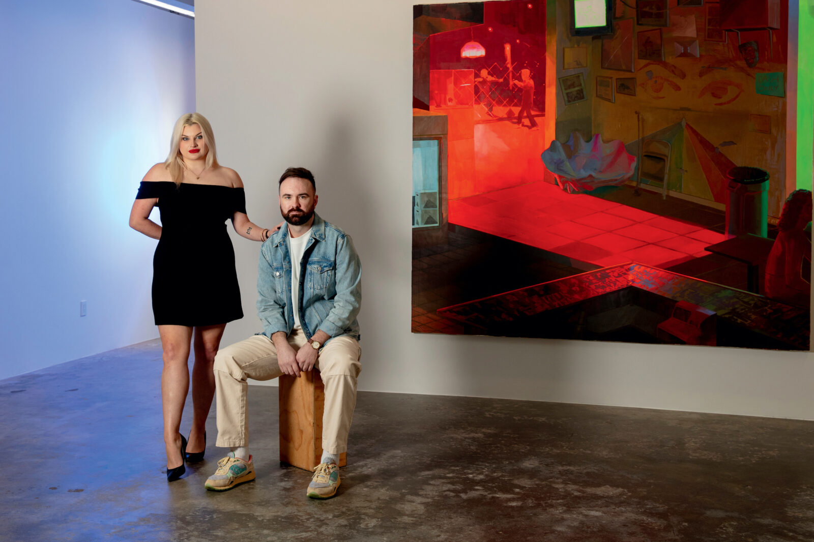 A man and woman stand in an art gallery in front of a red and black painting