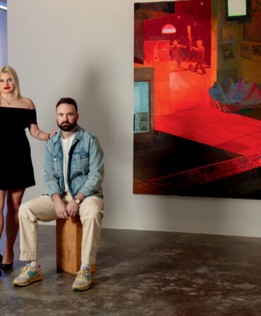 A man and woman stand in an art gallery in front of a red and black painting