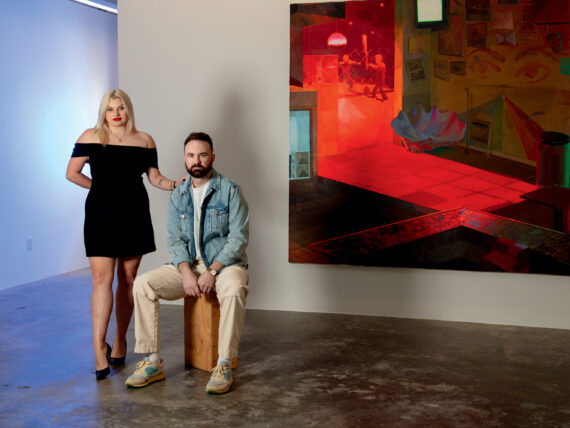 A man and woman stand in an art gallery in front of a red and black painting