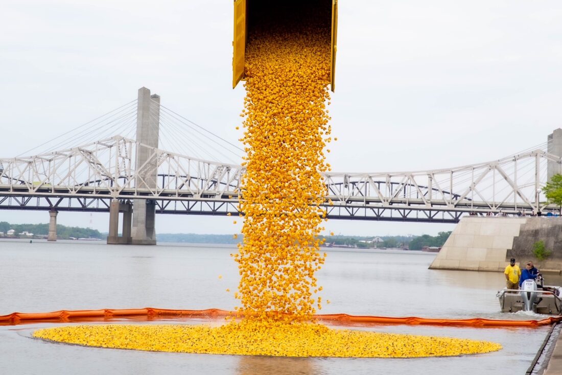A crane dumps yellow rubber ducks by the thousand into a river