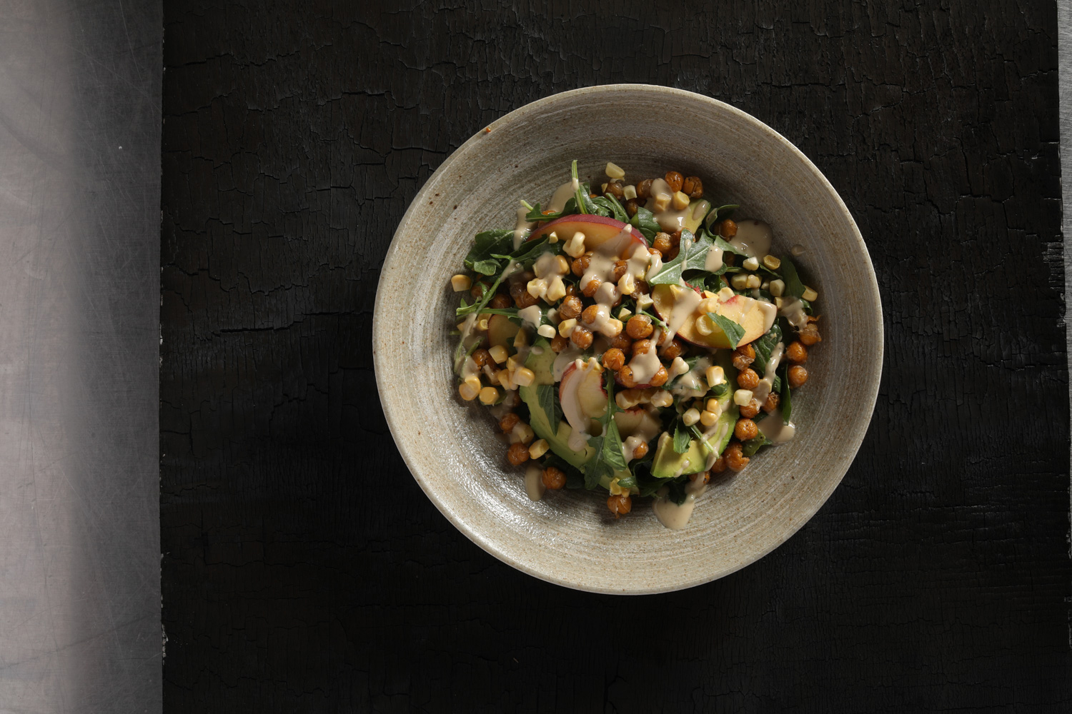 A white bowl with corn, avocado, and peach salad.