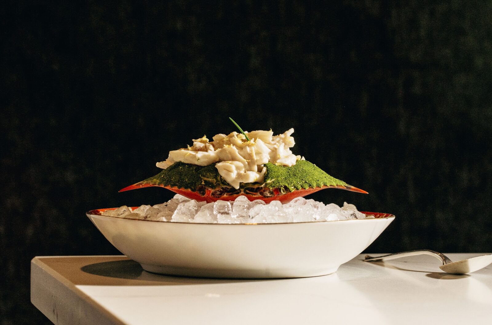 Deviled crab salad inside a crab on a bowl of ice