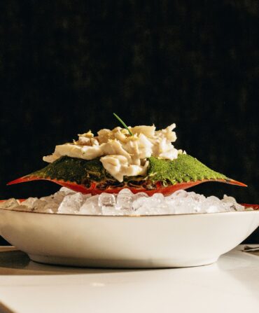 Deviled crab salad inside a crab on a bowl of ice