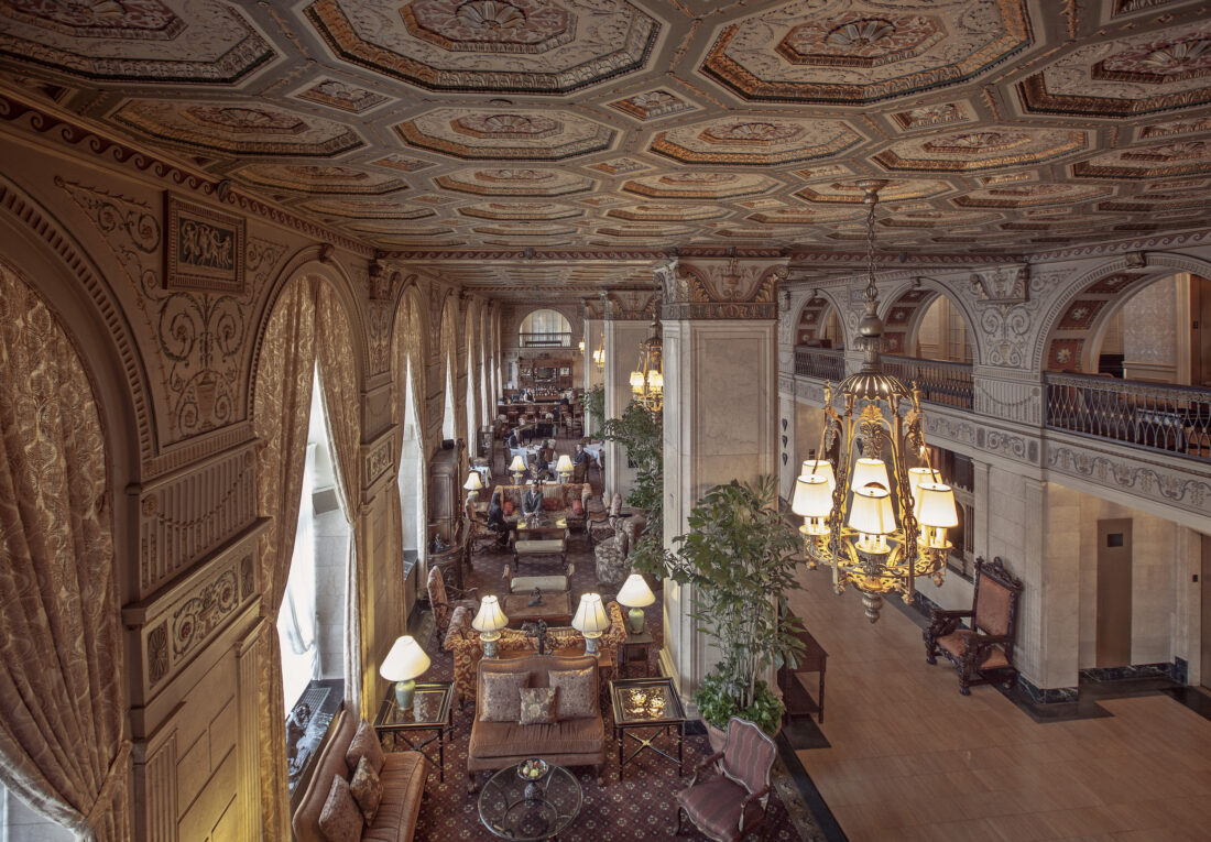 Inside a hotel lobby with ornate ceiling details and a chandelier