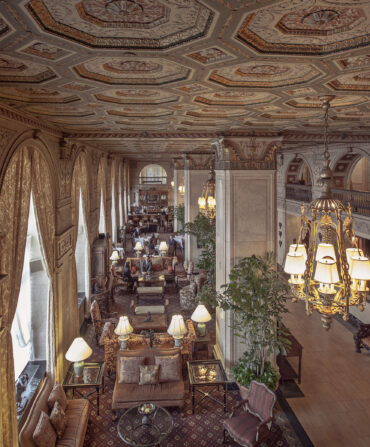 Inside a hotel lobby with ornate ceiling details and a chandelier