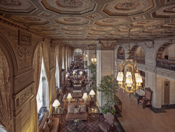 Inside a hotel lobby with ornate ceiling details and a chandelier
