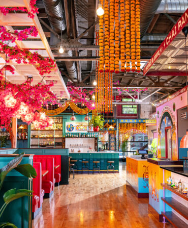 A colorful and bright restaurant space decorated with Indian street style and bright colors of pink, marigold, and teal