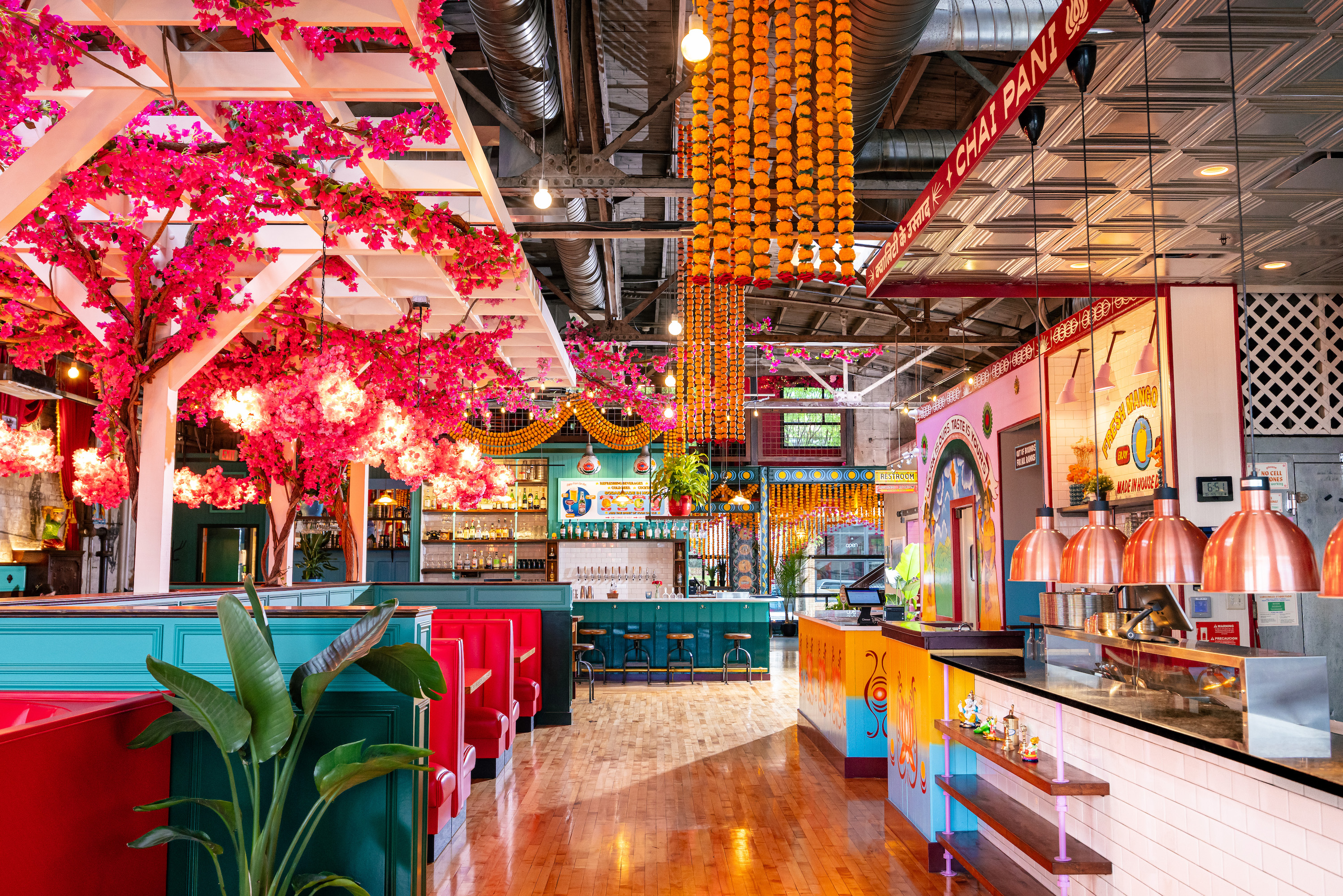 A colorful and bright restaurant space decorated with Indian street style and bright colors of pink, marigold, and teal