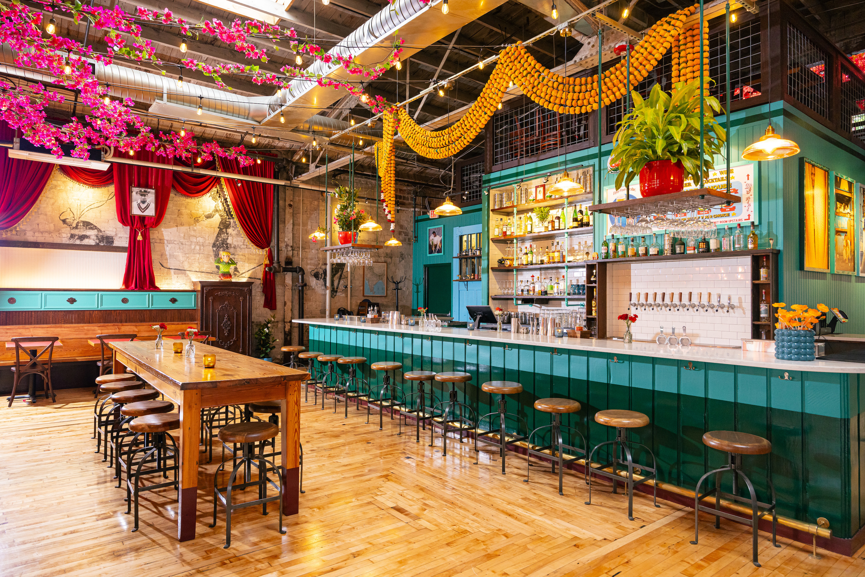 A bright teal bar with pink and yellow flowers hanging from the ceiling