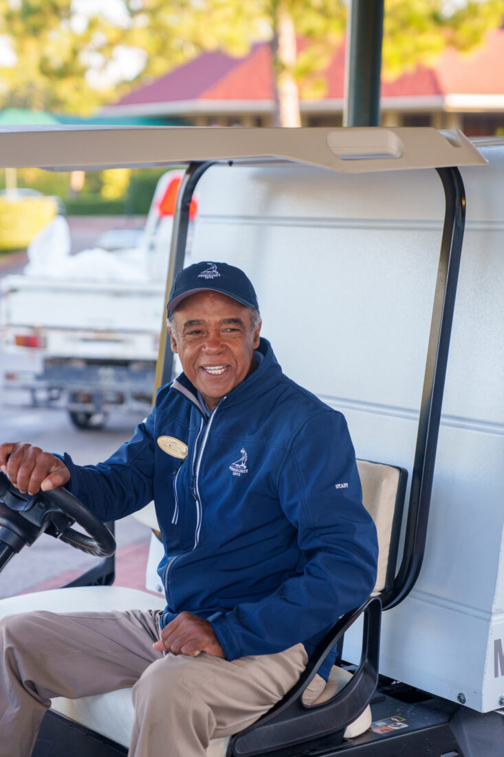 A man driving a golf cart smiles