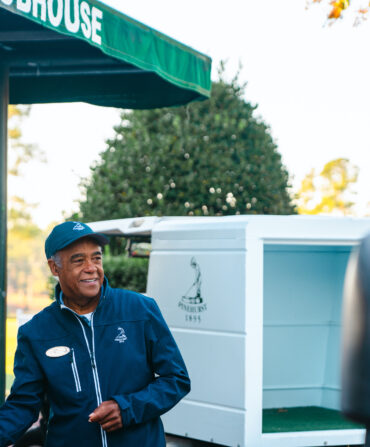 A man stands smiling under a golf tent